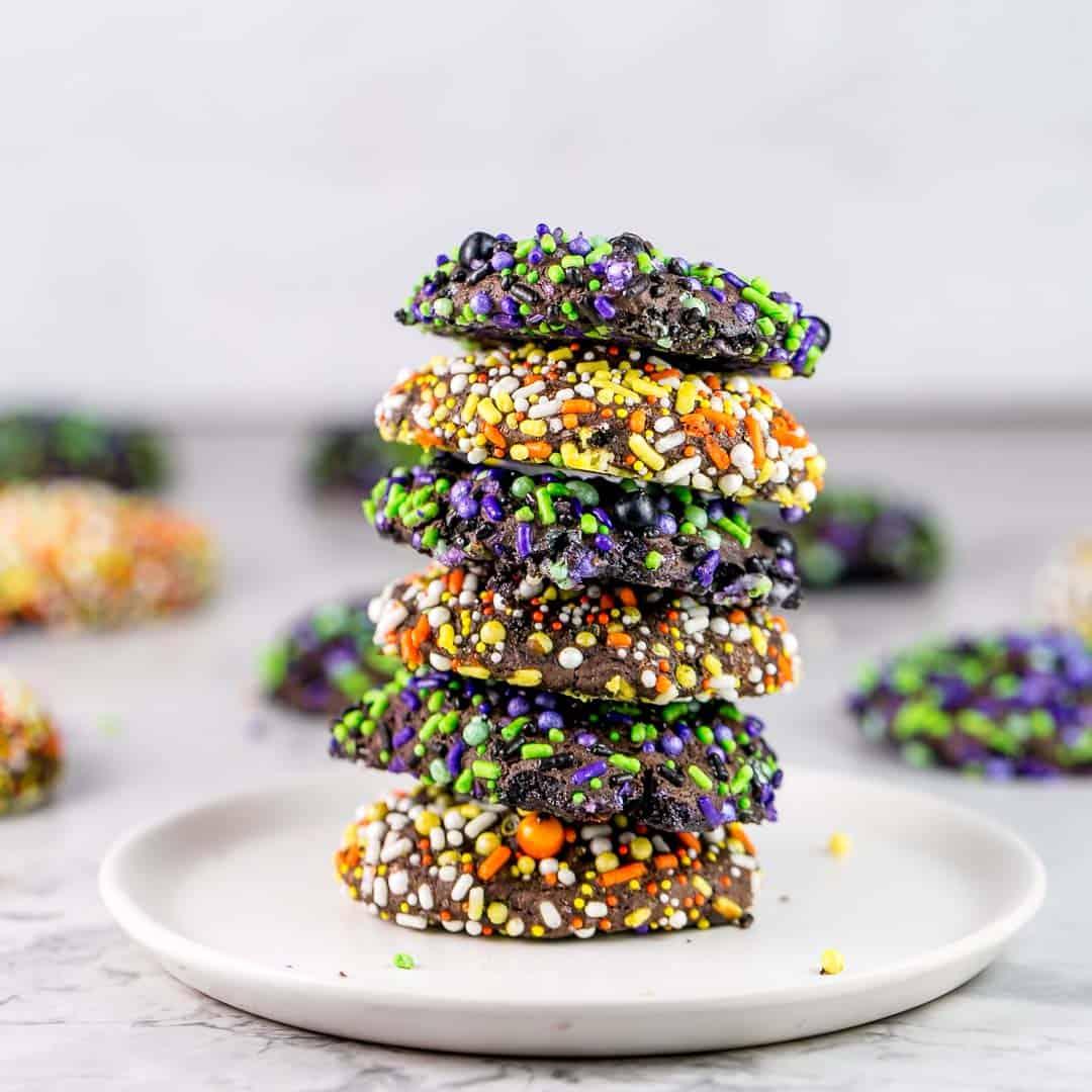 Stack of soft chocolate cookies coated with orange, yellow, purple and green Halloween sprinkles for a party