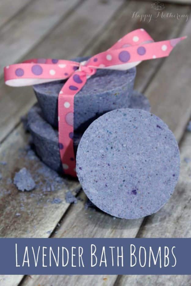 DIY lavender bath bombs graphic, pale purple round bath bombs tied with polka dot ribbon stacked on weathered wood