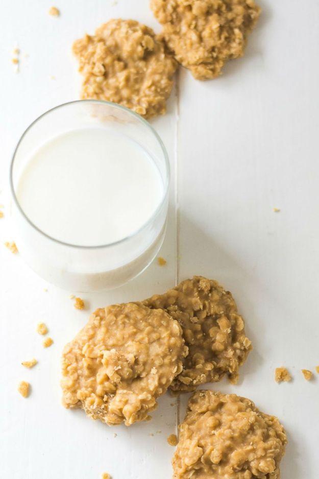 Peanut butter no bake cookies beside a tall glass of milk, pale oat cookies scattered on a white table
