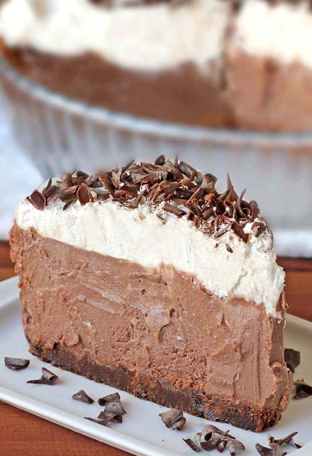 Chocolate cream pie slice on a white plate with a thick silky filling, whipped cream and chocolate curls