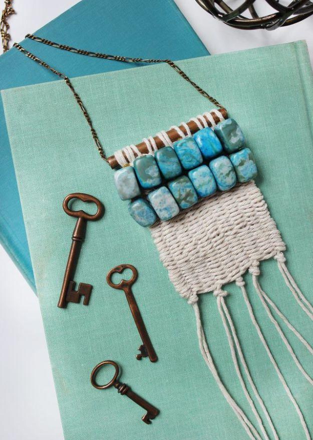 Woven cream twine necklace with a turquoise bead bar and long fringe, on teal fabric beside three old keys