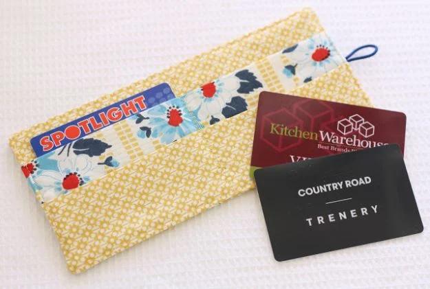 Loyalty card wallet, a yellow and blue floral fabric card sleeve holding store loyalty cards on white waffle