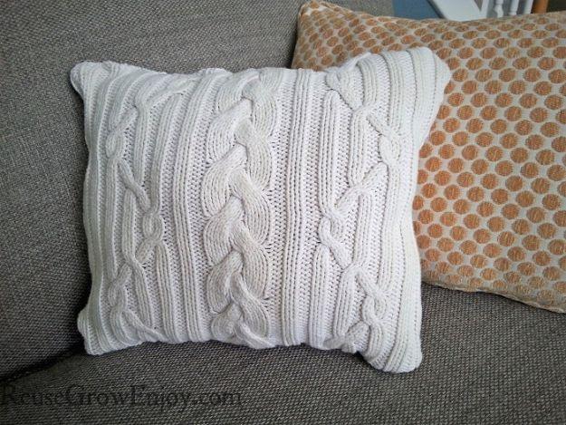 DIY sweater pillow, a cream cable knit cushion resting on a grey sofa next to an orange polka dot pillow