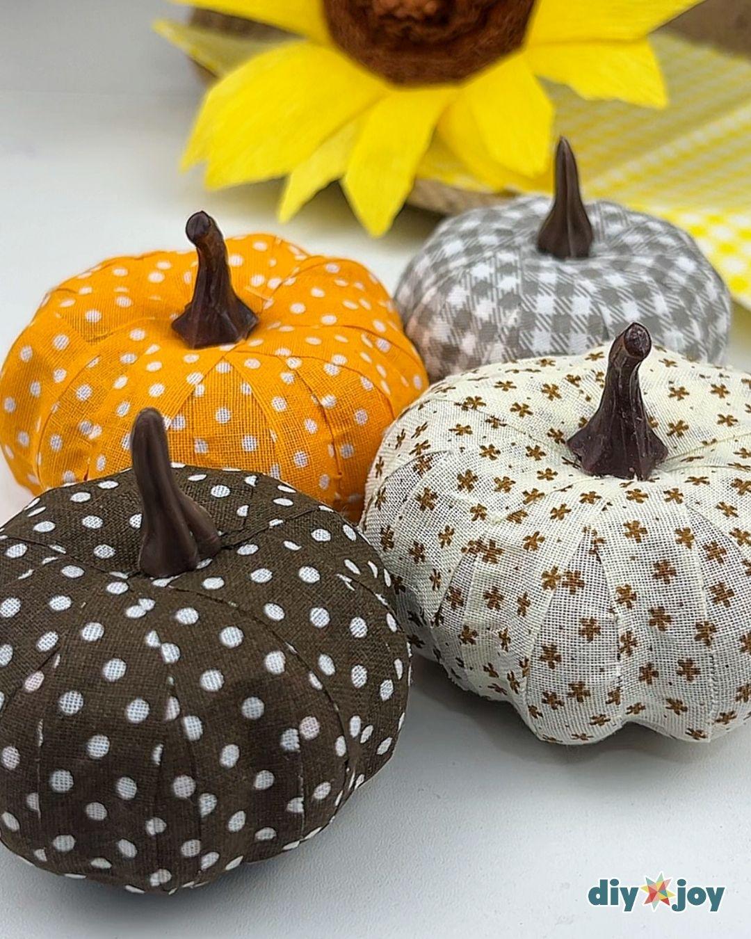 Fall Table Decor - the four finished fabric pumpkins shot at an angle with a paper sunflower and gingham fabric behind them