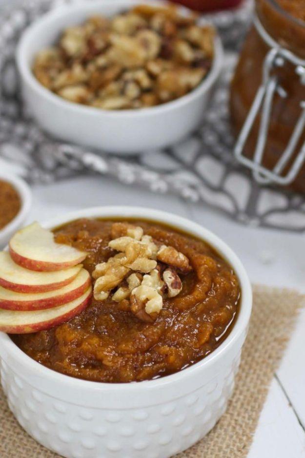 White bowl of thick pumpkin applesauce topped with apple slices and walnuts beside a bowl of chopped nuts