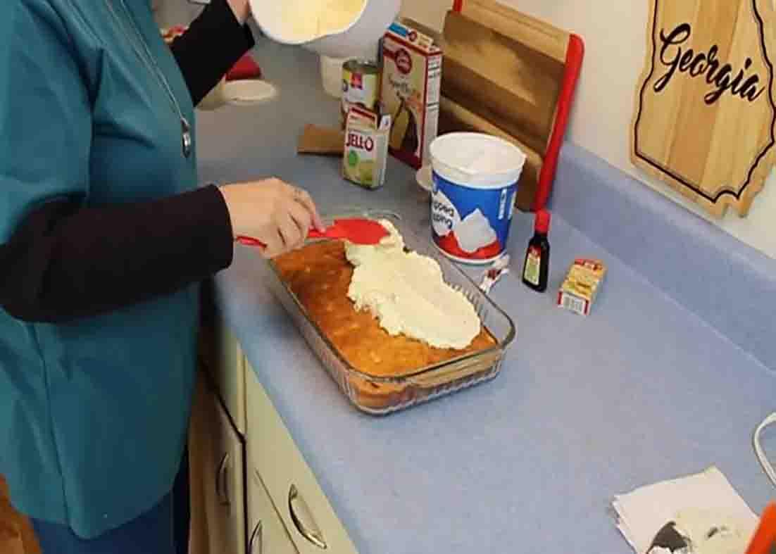 Spreading the pineapple frosting over the cake