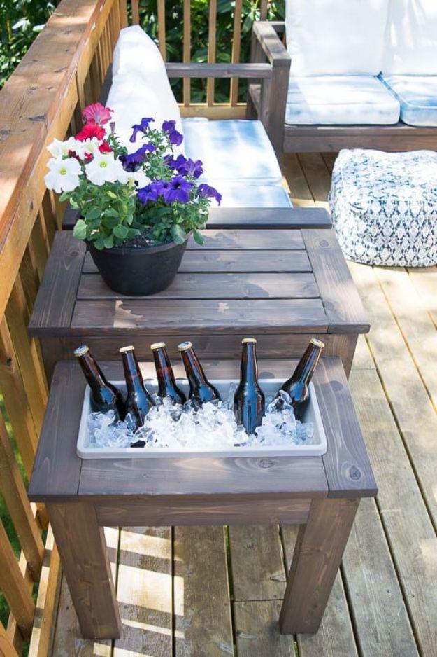 DIY end table with a built in ice bucket full of bottles and a second tier holding a pot of petunias on a deck