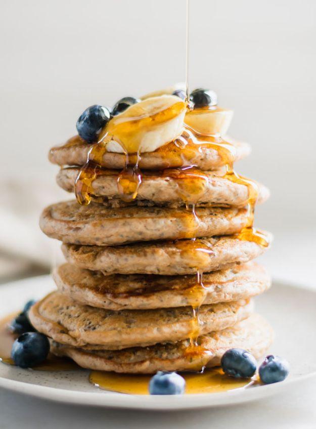 Tall stack of vegan chia seed pancakes with sliced banana, blueberries and syrup running down the sides