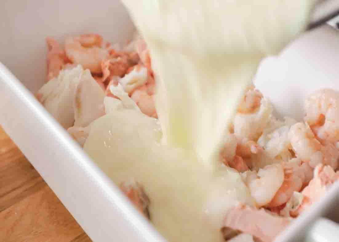 Pouring the sauce over the fish and prawns