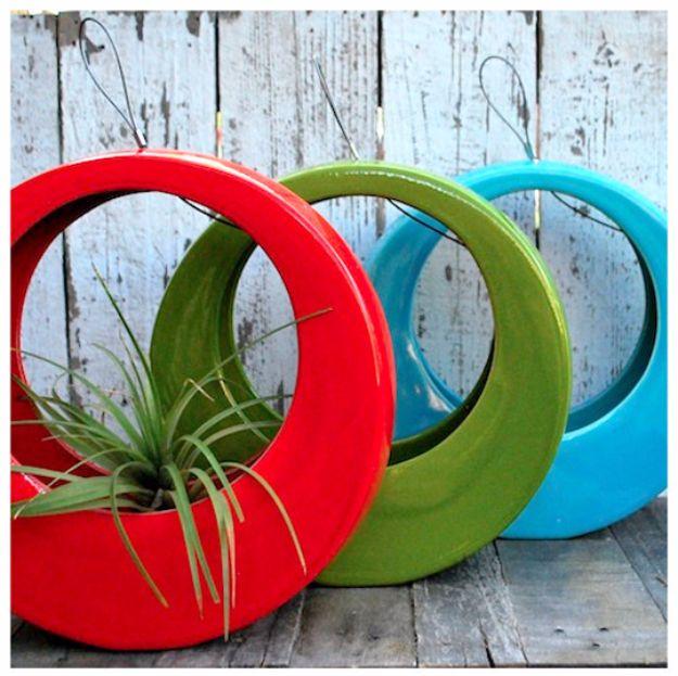 Three old tires cut into loops and painted glossy red, green and turquoise hanging on a weathered white wall