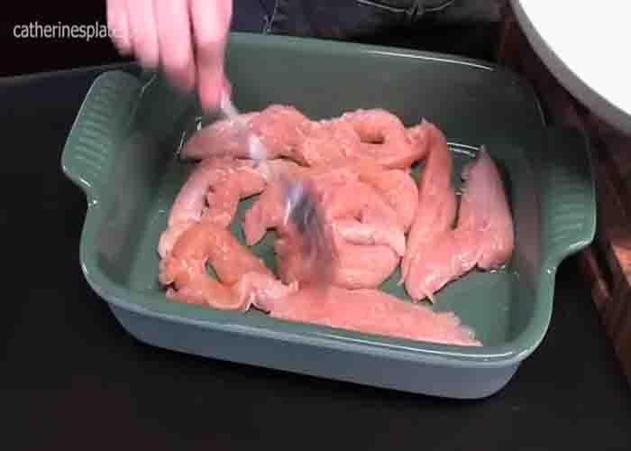 Laying the chicken tenders on the bottom of the casserole dish