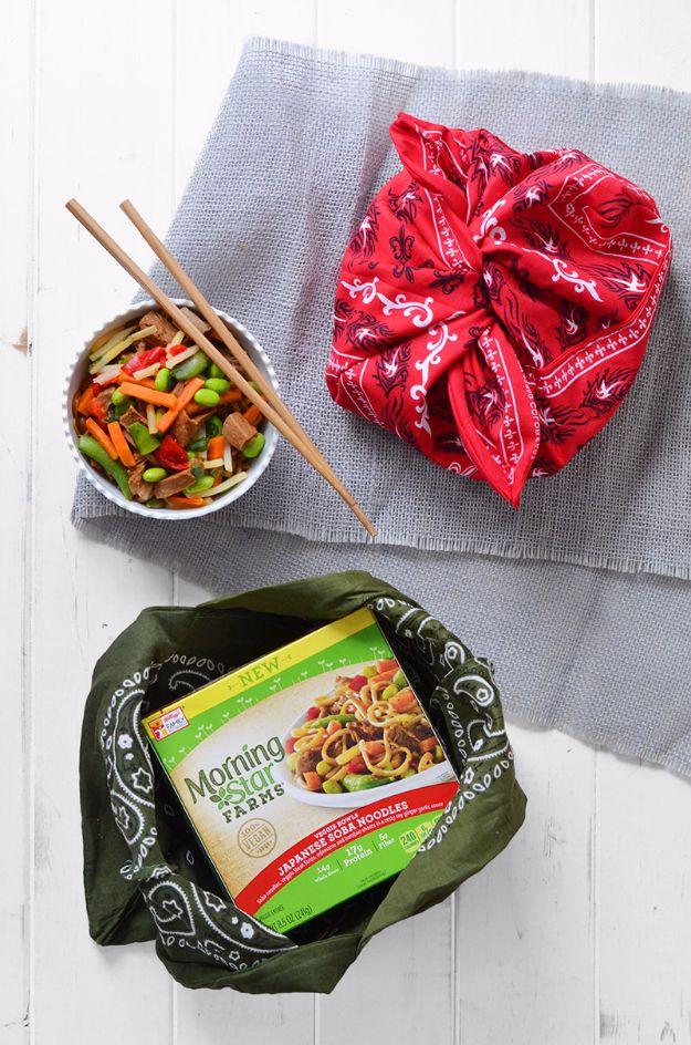 DIY bandana bento bags, a red furoshiki knot and a green wrapped bundle beside stir fry and chopsticks
