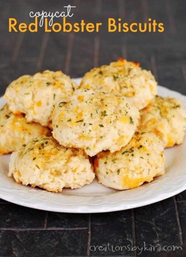 Copycat Red Lobster biscuits, pale cheddar drop biscuits brushed with parsley garlic butter and piled on a white plate