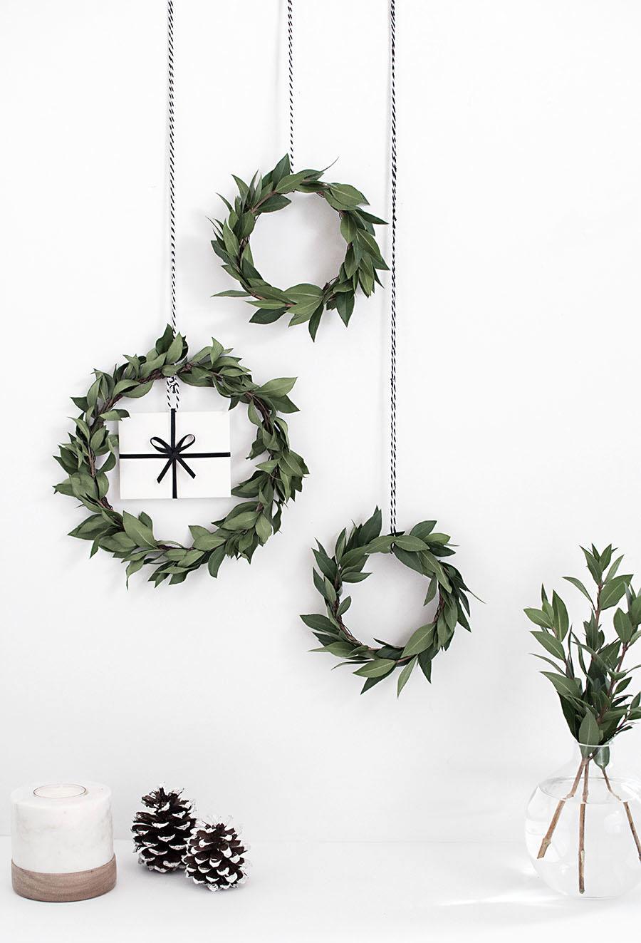 Three mini green leaf wreaths hanging on black and white twine, one holding a white gift card tied with black ribbon