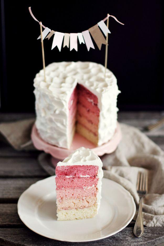 Pink rainbow cake with a bunting topper and a slice showing five graded pink layers with jam between them