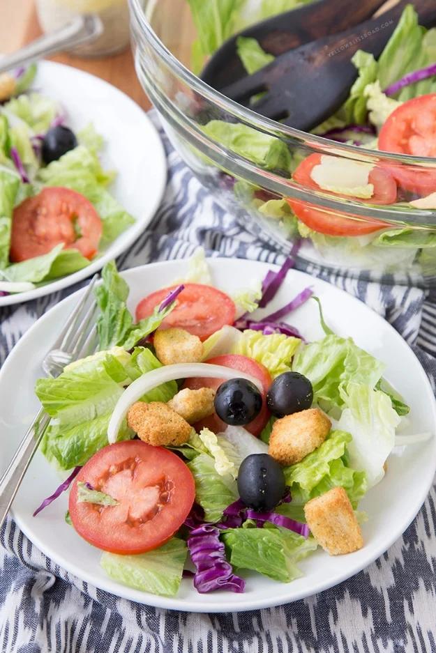 Olive Garden salad copycat with romaine, red cabbage, tomatoes, black olives, pepperoncini and croutons