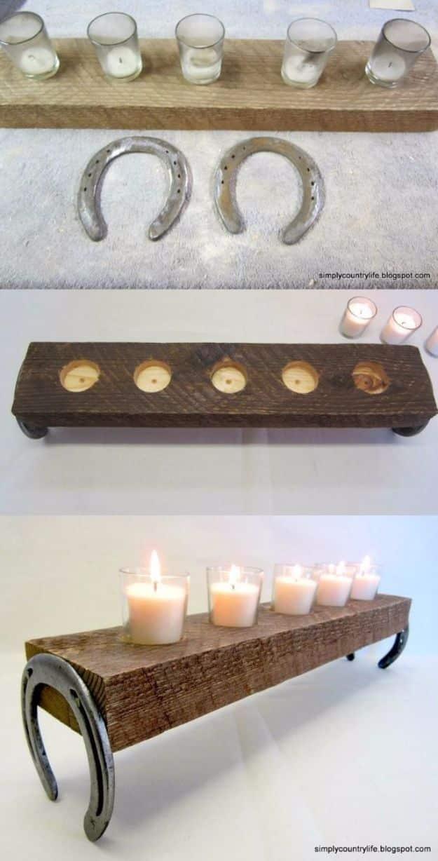 Two rusted horseshoes bolted to a thick wood slab with a cream candle between them, primitive country craft decor