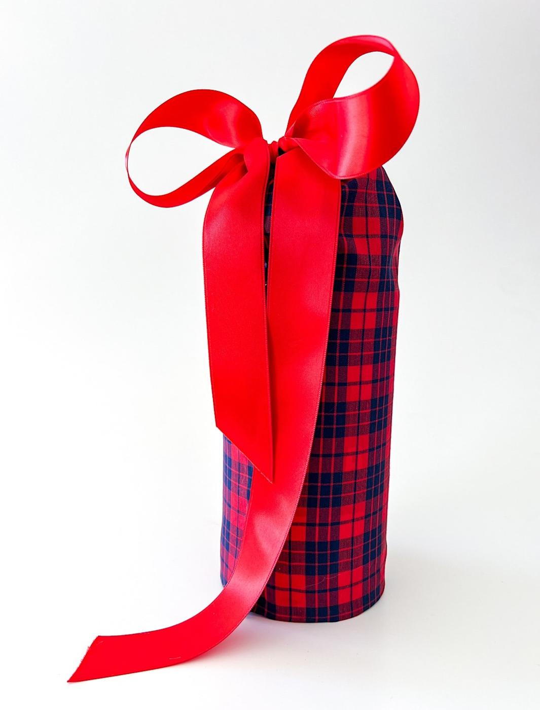 An oatmeal canister covered in red and navy plaid fabric and tied at the top with a wide red satin bow