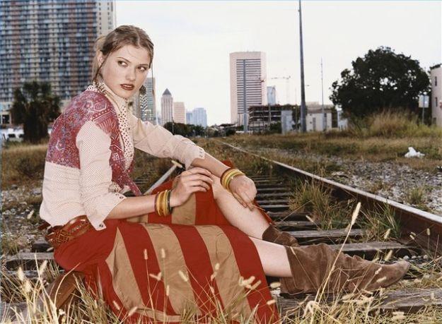 Woman sitting on railway tracks in a rust and cream striped crinkled broomstick skirt and pale blouse