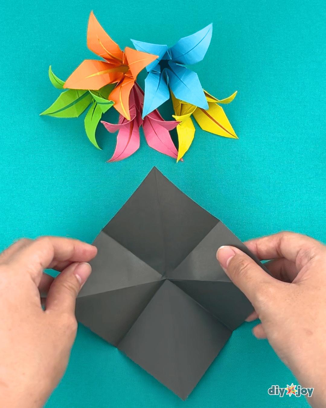 DIY flower project underway, paper sides folded in toward the center line to shape the petals of a paper lily