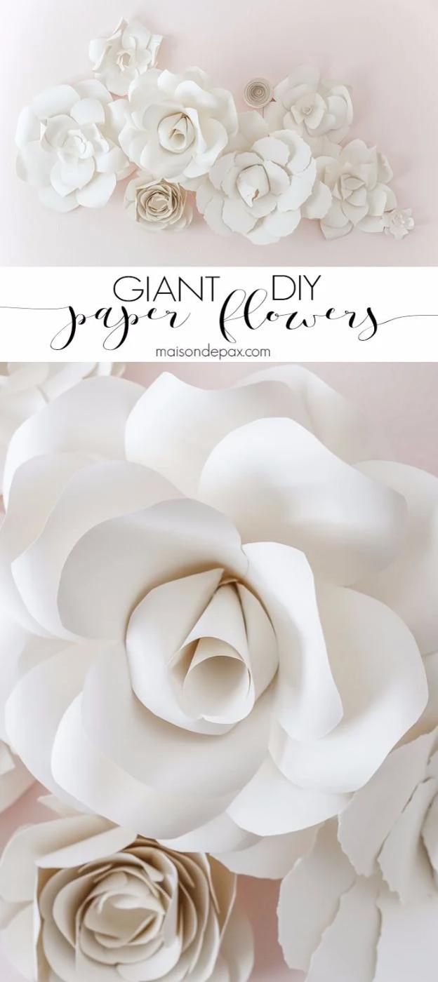 DIY giant paper flowers, oversized cream and white paper roses mounted in a cluster on a pale nursery wall