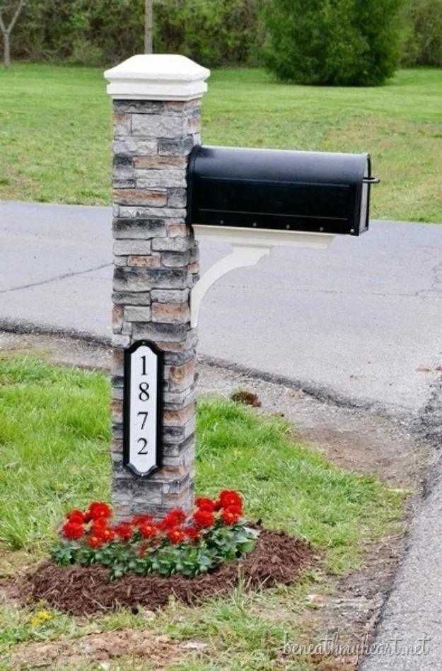 DIY curb appeal mailbox makeover with a gray stacked stone post, black mailbox, reflective address plate and red flowers