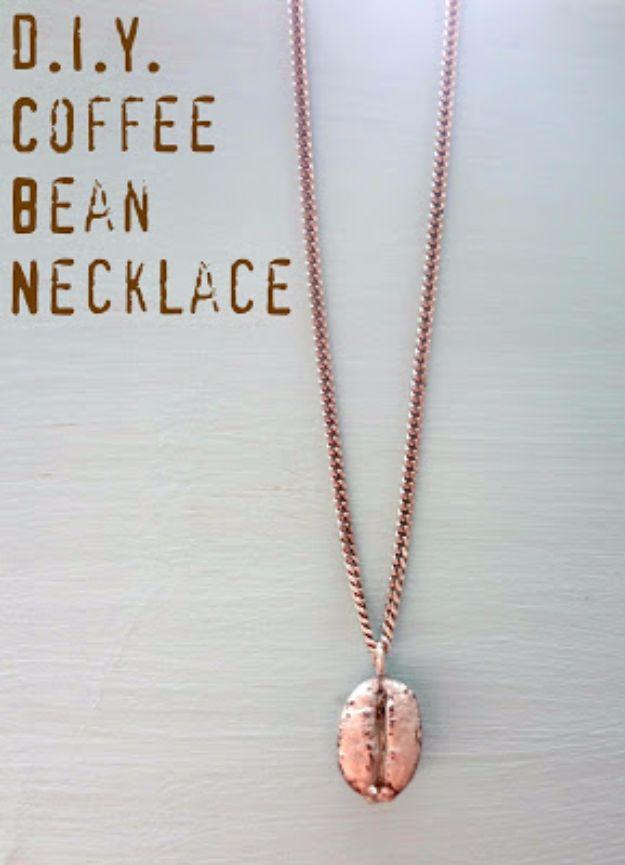 DIY coffee bean necklace, a single coffee bean painted rose gold hanging from a fine chain on a pale wooden surface