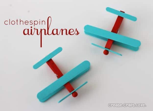 Two clothespin airplanes painted teal and red with craft stick wings and wooden bead propellers on a white background