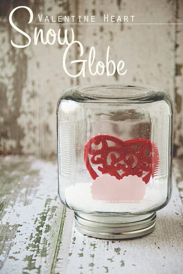 Mason jar snow globe with a small heart scene glued inside the lid and glitter suspended in water for a handmade gift