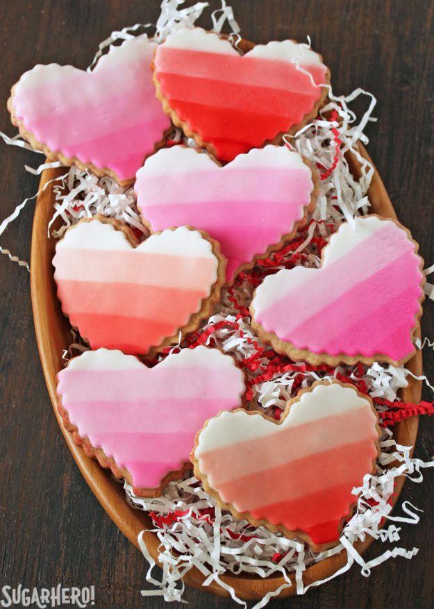 Brown butter heart cookies topped with hand painted fondant designs in soft colors on a wooden board