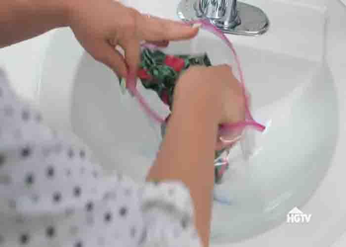 Placing the clothes inside the ziplock witk liquid detergent