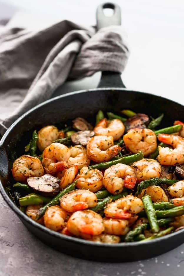 Garlic shrimp asparagus skillet in a cast iron pan with pink shrimp, asparagus pieces and sliced mushrooms
