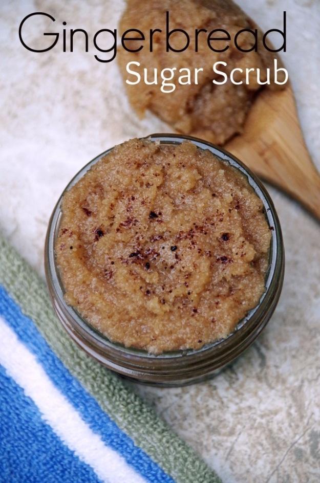 Gingerbread sugar scrub in a glass jar dusted with cinnamon, a wooden scoop resting on a striped towel