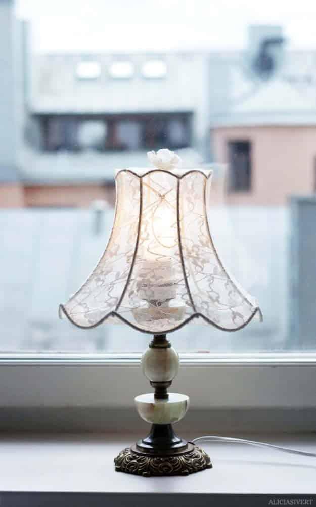Lampshade covered with lace tights, a lit table lamp with a scalloped lace covered shade on a windowsill