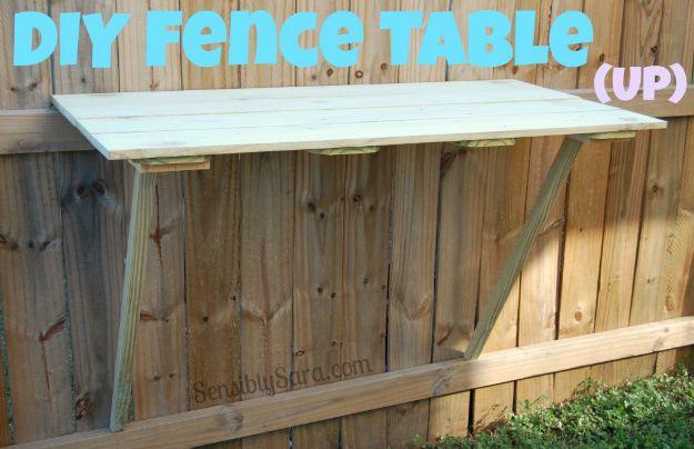 DIY fence table, a mint painted slatted table hinged up flat against a tall wooden fence on one angled brace