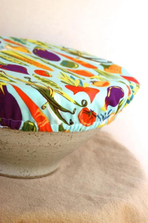 Easy bowl cover sewn in bright vegetable print cotton with elasticated edges, stretched over a speckled stoneware bowl