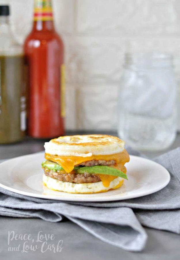 Keto breakfast sandwich with sausage patties, cheese and avocado stacked between two round fried eggs