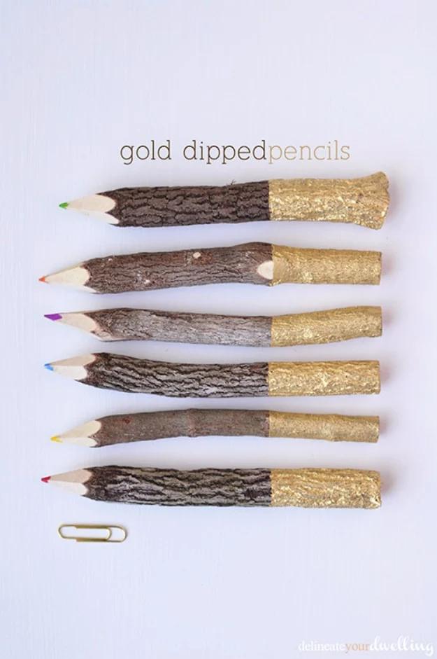 Six plain wooden pencils with gold painted ends, tied into a bundle with cream ribbon on white linen