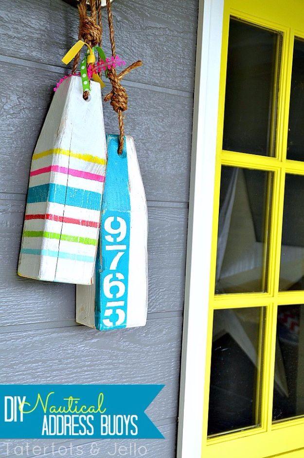 DIY nautical address buoys cut from pine, painted in stripes with numbers, hung on rope by a yellow door