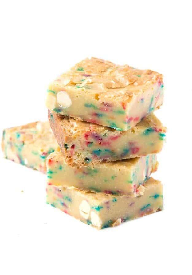 Funfetti white chocolate brownies stacked four high with colorful sprinkles through a pale golden crumb