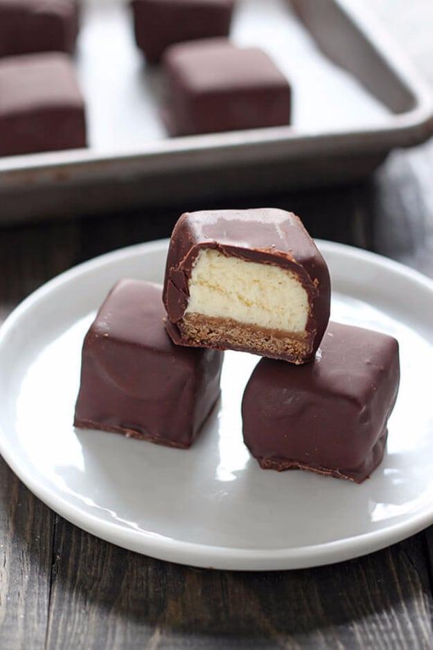Chocolate covered cheesecake bites, small squares of baked cheesecake dipped in dark chocolate on a tray