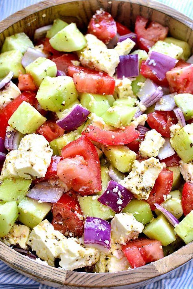 Tomato cucumber feta salad in a wooden bowl with chopped tomatoes, cucumber, red onion and cubed feta