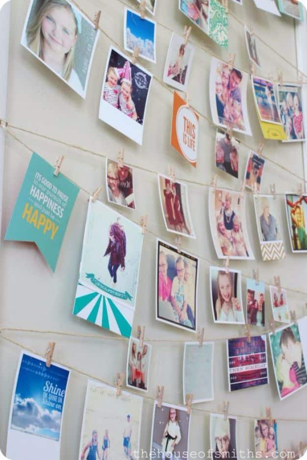Wall strung with rows of twine holding dozens of clipped photos, cards and patterned papers on small wooden clothespins