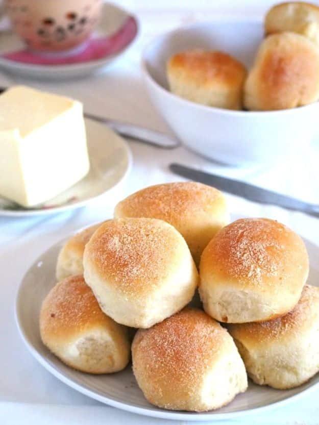 Filipino pandesal rolls coated in breadcrumbs and baked golden, stacked warm in a basket lined with cloth