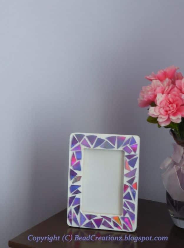 Small white picture frame covered in a mosaic of purple and pink iridescent CD triangles on a side table