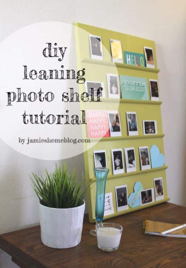 Yellow green leaning photo shelf with five quarter round ledges holding instant film prints, beside a plant and a candle