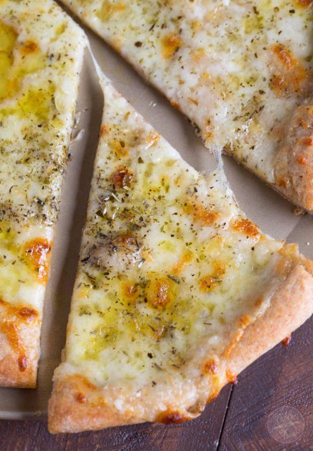 A slice cut free from a homemade white pizza glossy with olive oil, mozzarella and dried oregano flecks