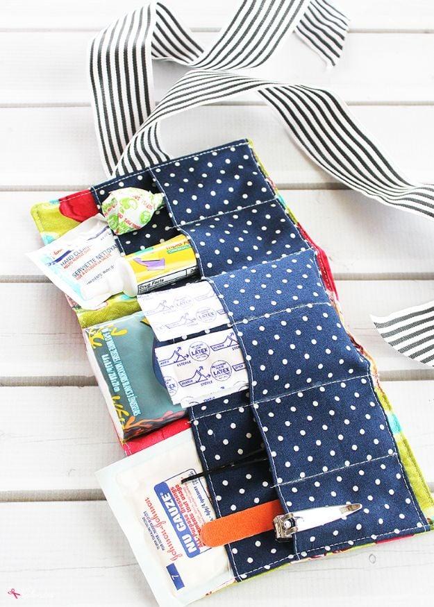 A small quilted first aid pouch unzipped to show elastic loops holding band-aids and ointment inside.