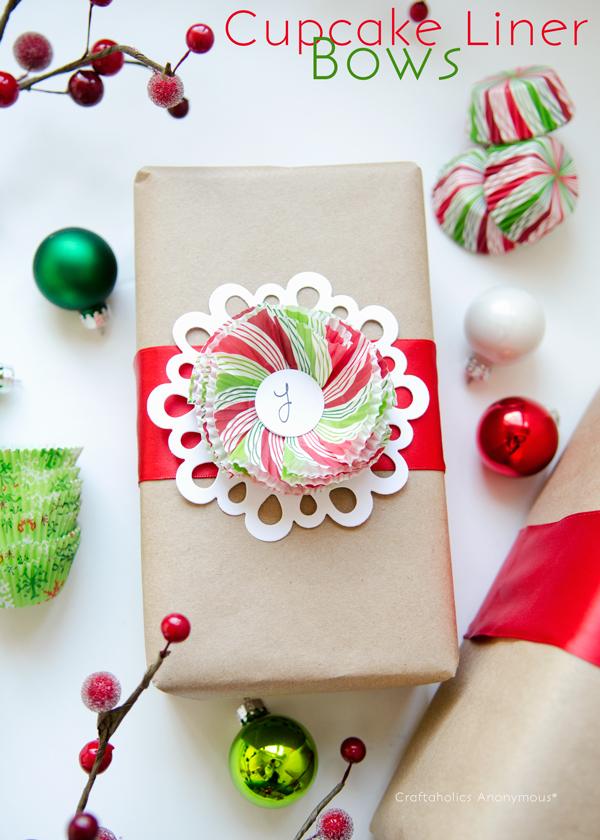 A kraft parcel with a red ribbon and a layered red and green cupcake liner rosette on a white paper doily