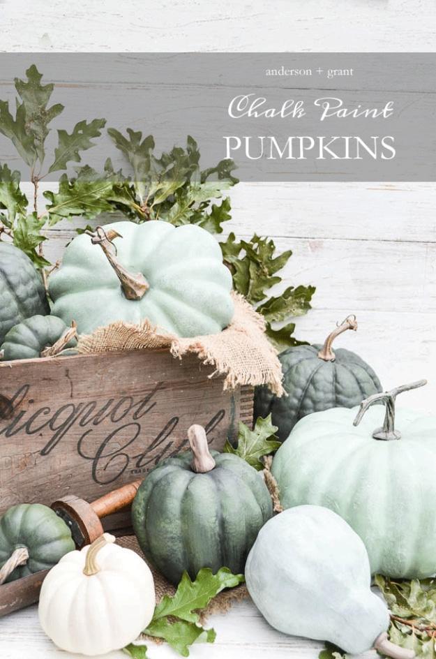 Sage and gray green chalk painted pumpkins piled in and around a wooden crate with oak leaves and burlap
